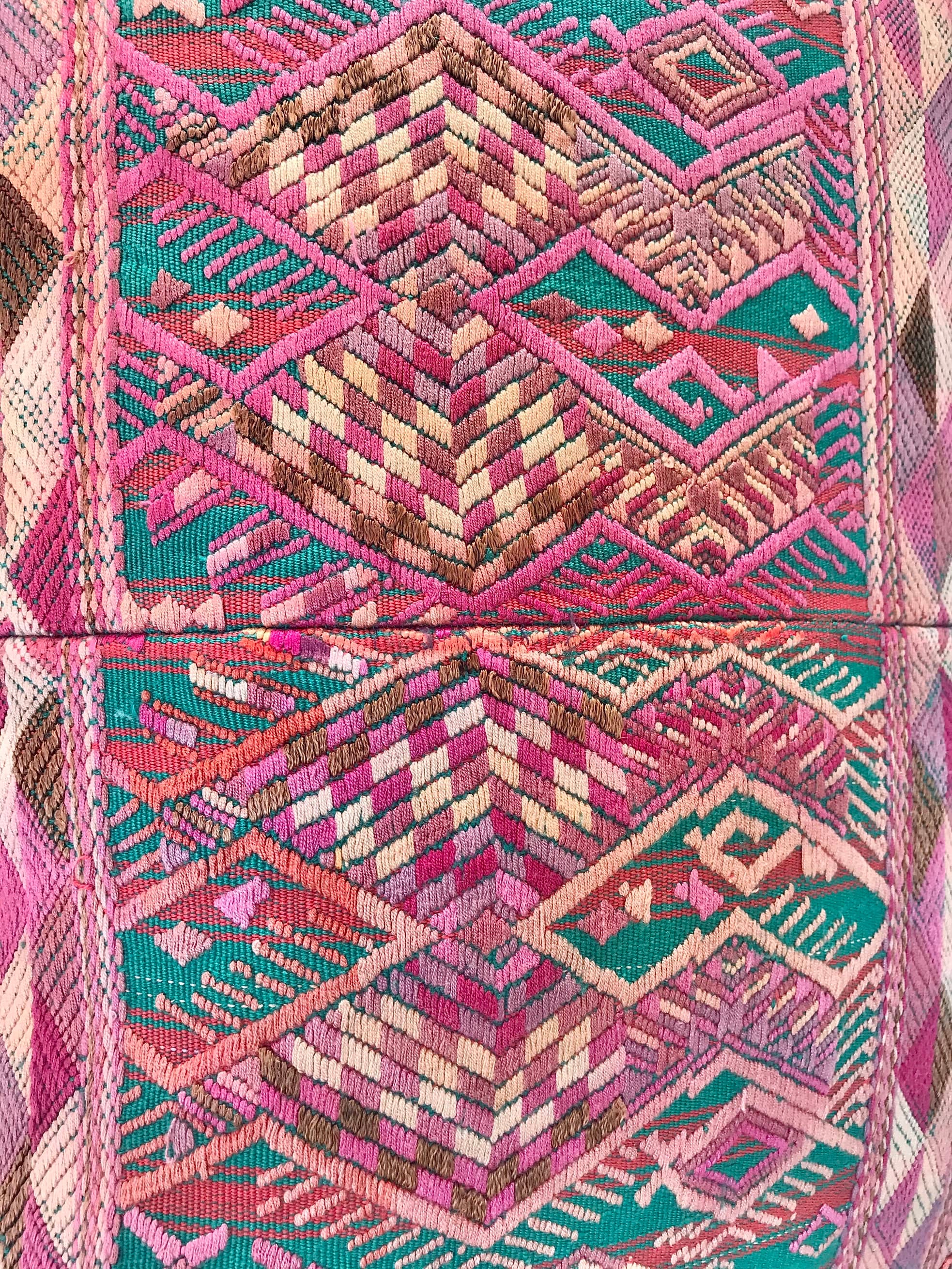 Guatemalan embroidered huipil pillow. A pink and turquoise striped vintage textile with stylised horses.