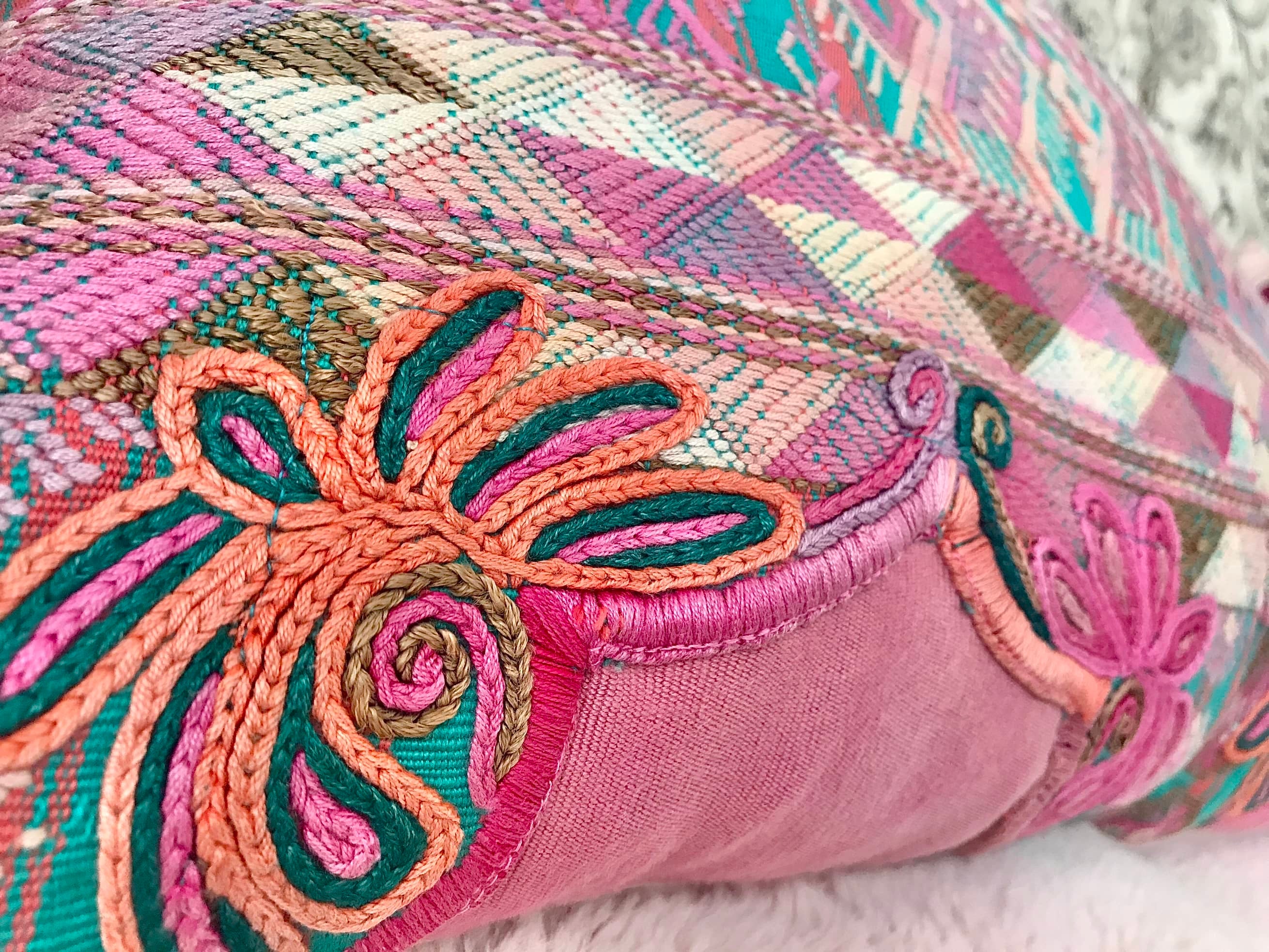 Guatemalan embroidered huipil pillow. A pink and turquoise striped vintage textile with stylised horses.