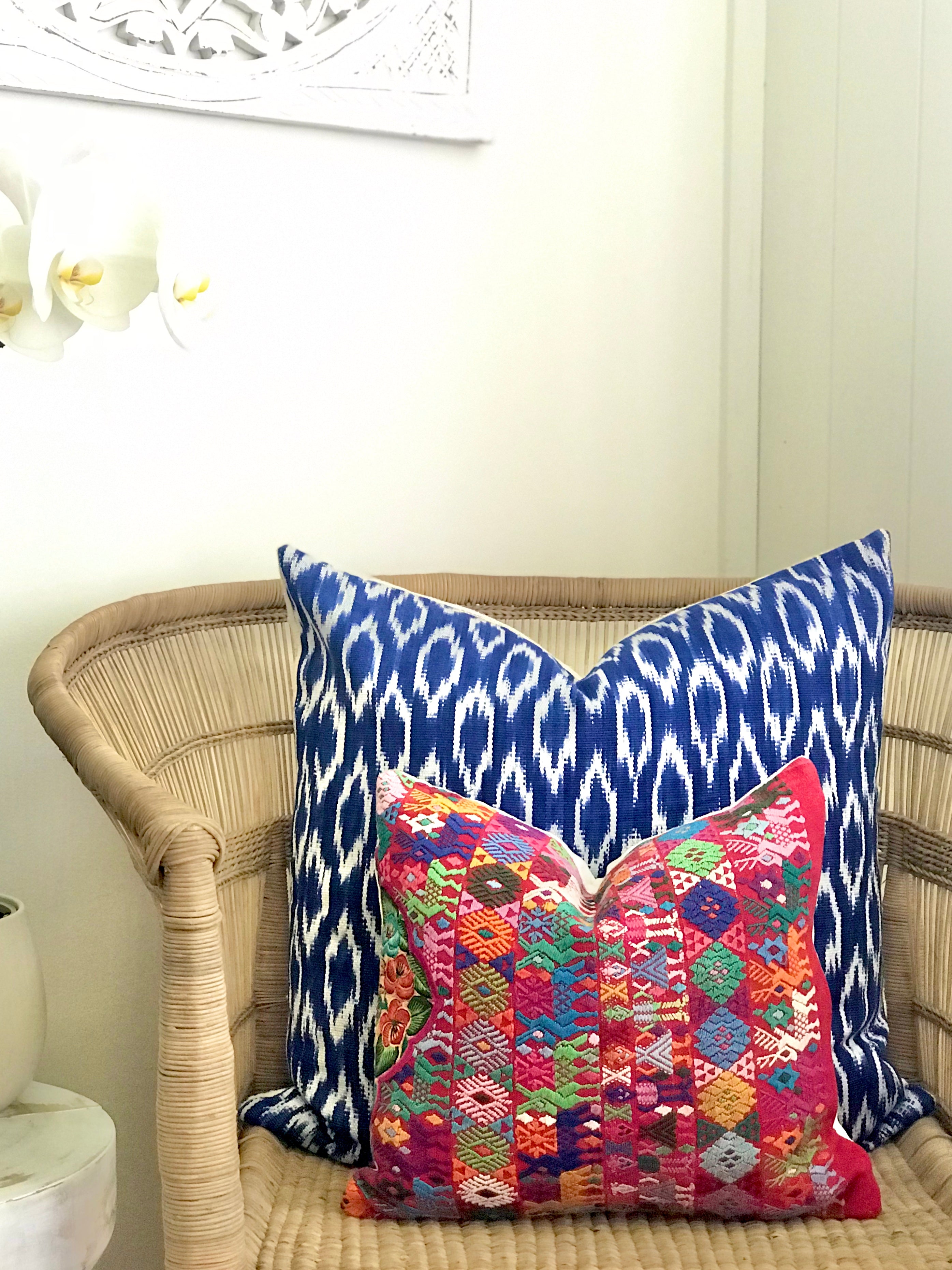 A pair of Guatemalan Huipil Pillows, vintage, hand embroidered Coban textile of brightly coloured tribal figures over a red cotton
