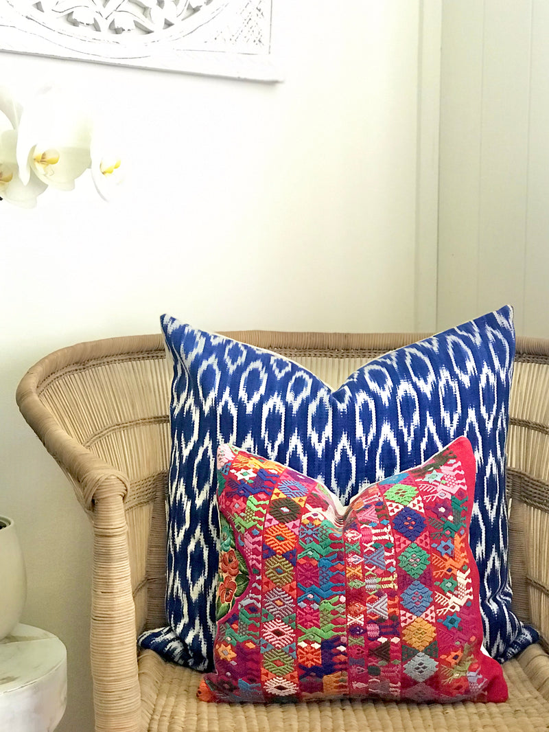 A pair of Guatemalan Huipil Pillows, vintage, hand embroidered Coban textile of brightly coloured tribal figures over a red cotton