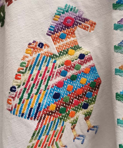 White huipil with colorful peacocks