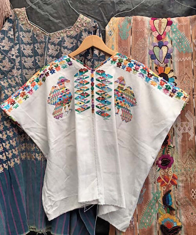 White huipil with colorful peacocks